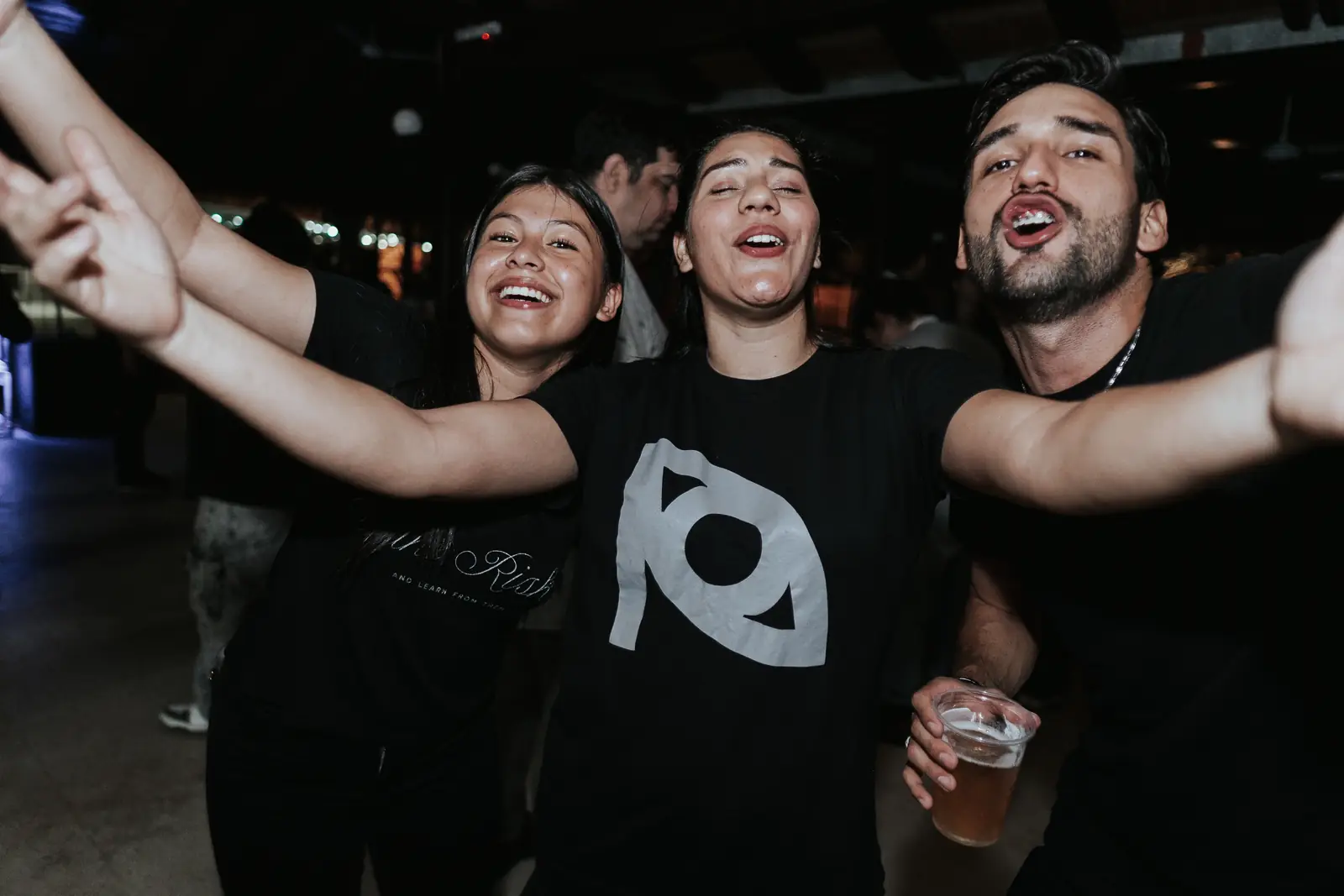 Tres participantes cantan y festejan con los brazos en alto en la pista del After 2026