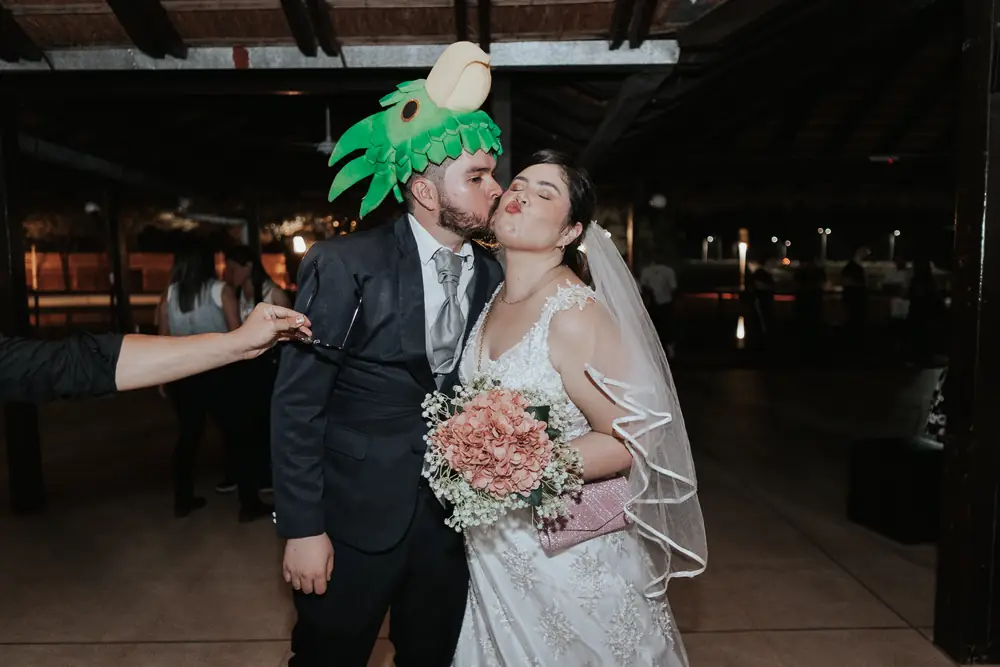 Una pareja vestida de novios se besa con un ramo de rosas en el After
