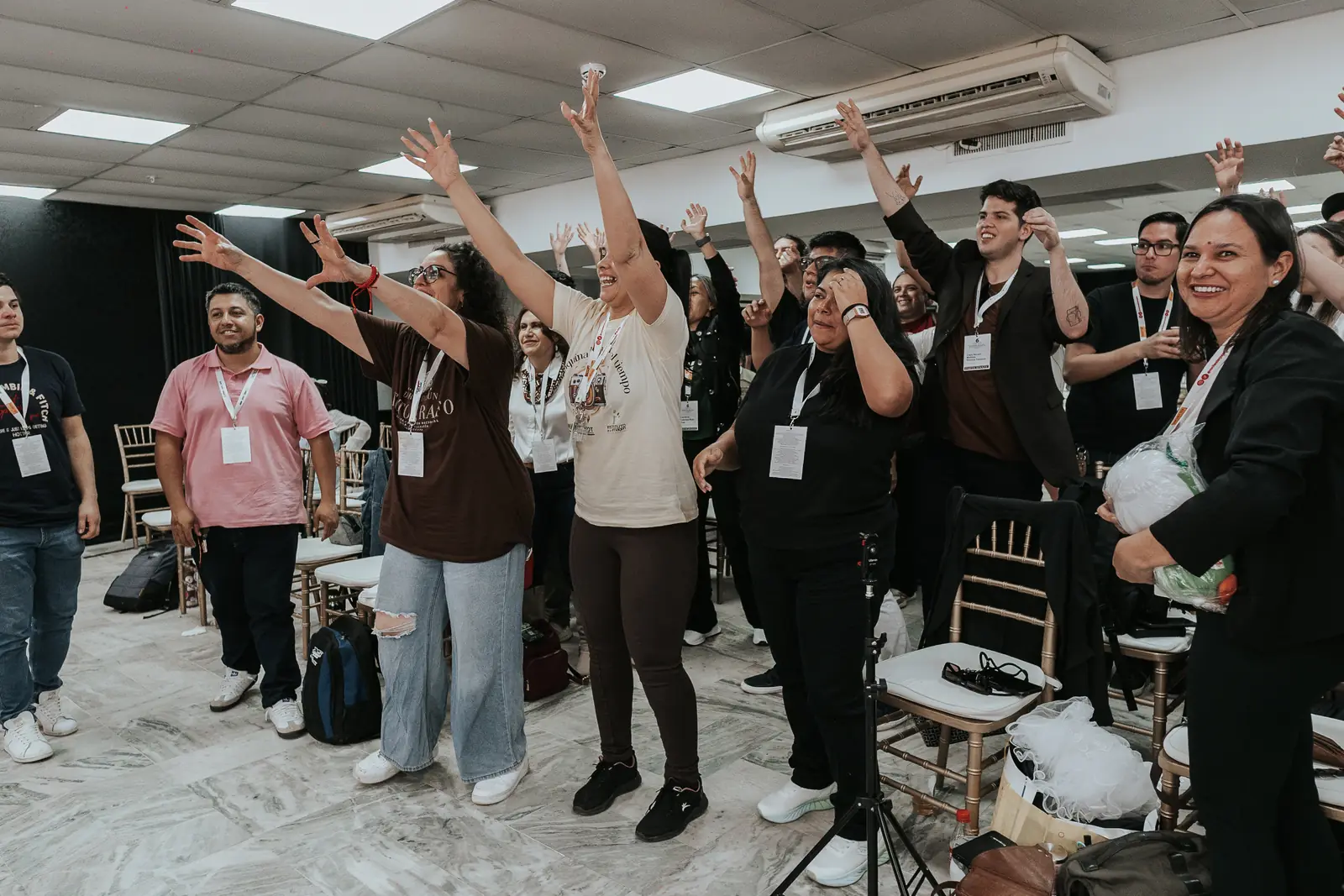 El público de pie con los brazos en alto durante una dinámica en el salón
