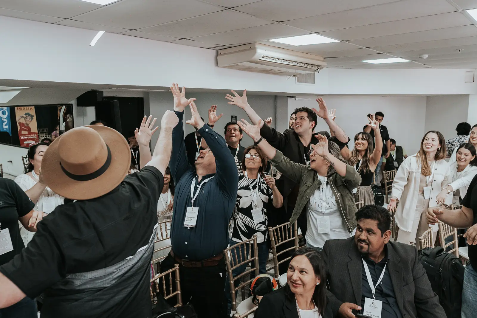 Un salón lleno de gente festejando con los brazos arriba